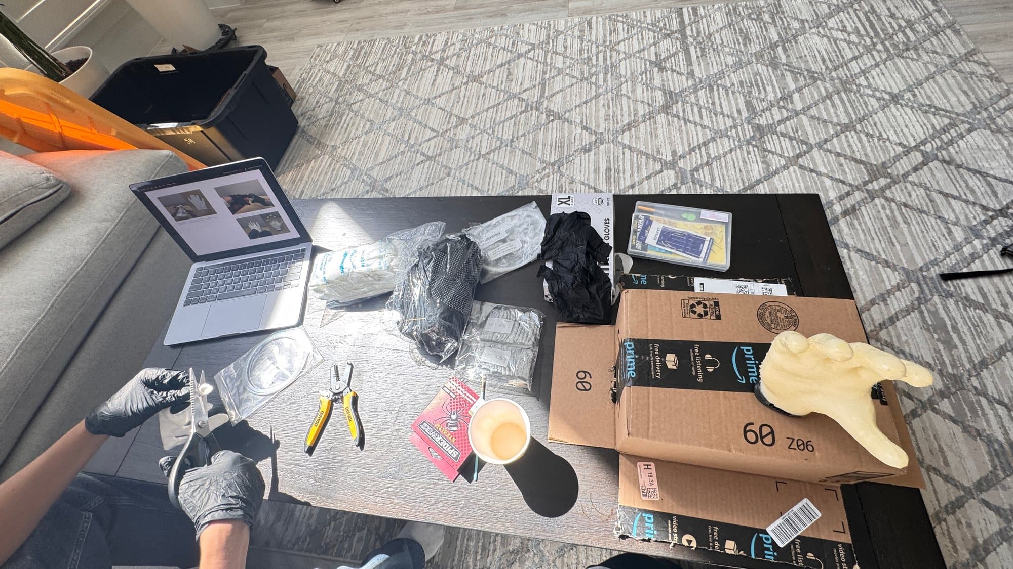 Our workspace for Phase 2: foam hand, gloves, tools, and the build guide on the laptop